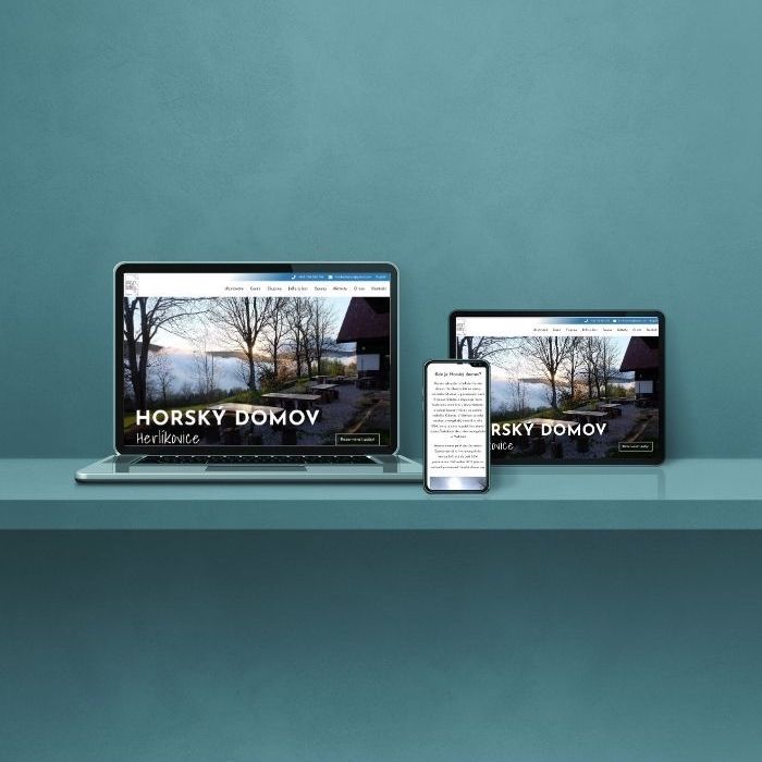 Electronic devices including laptop, tablet, and phone neatly arranged on a table, each showing the homepage of the Mountain Home website.